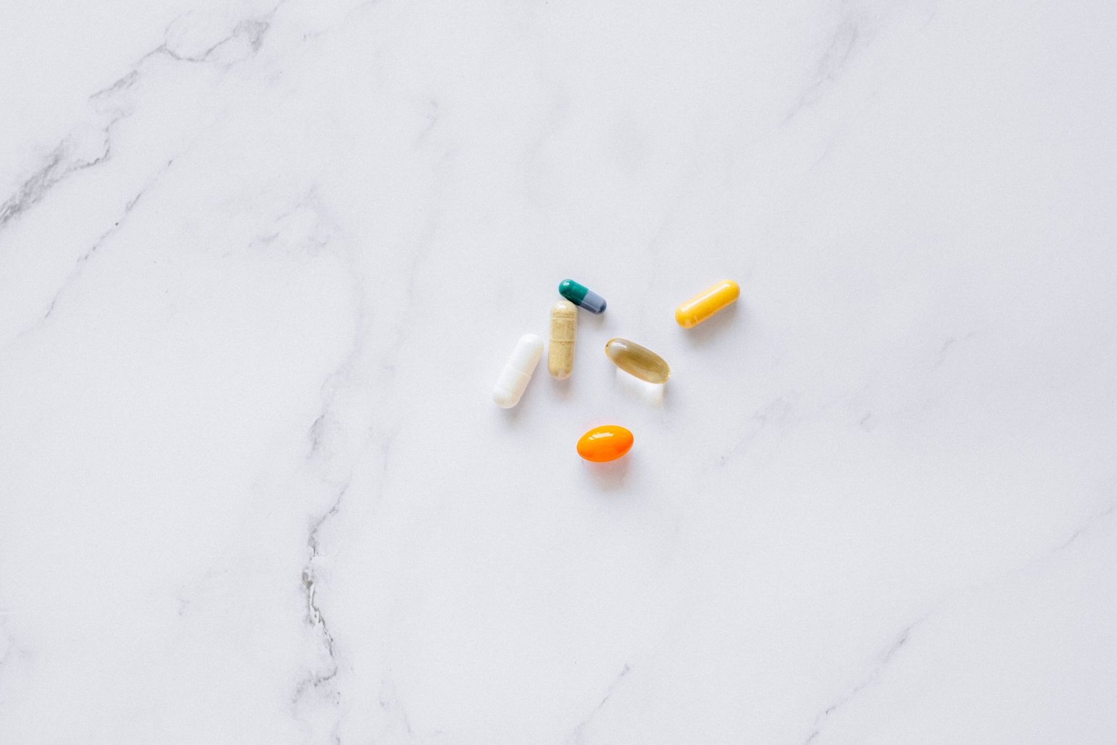 A few assorted capsules and tablets on white marble