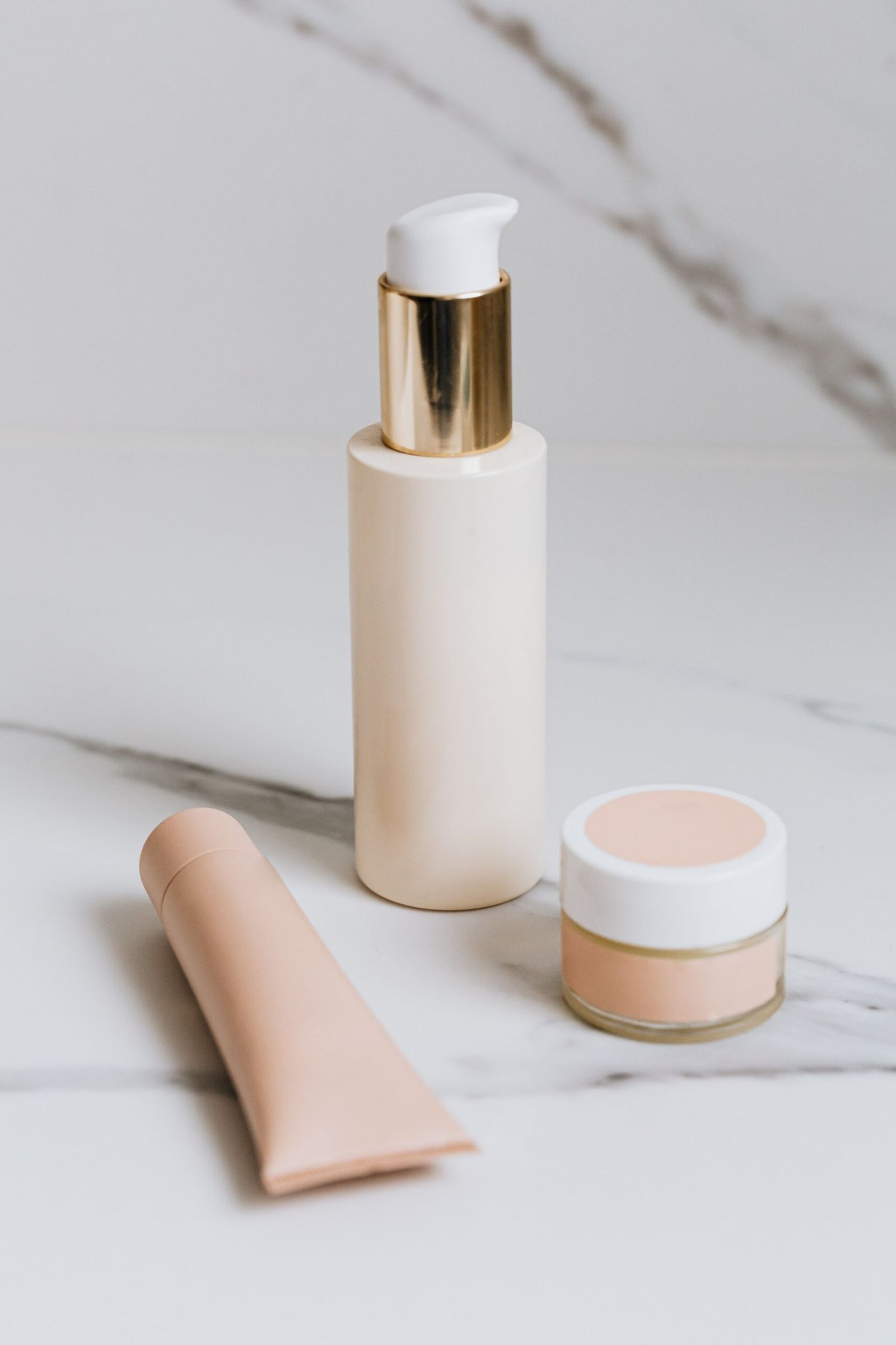 Skincare tube, pump bottle and jar on a marble surface
