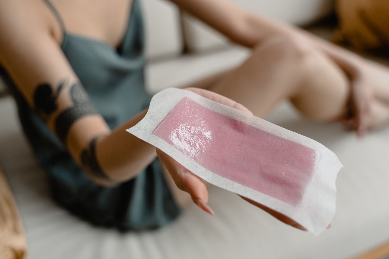 Hand holding a hair removal wax strip