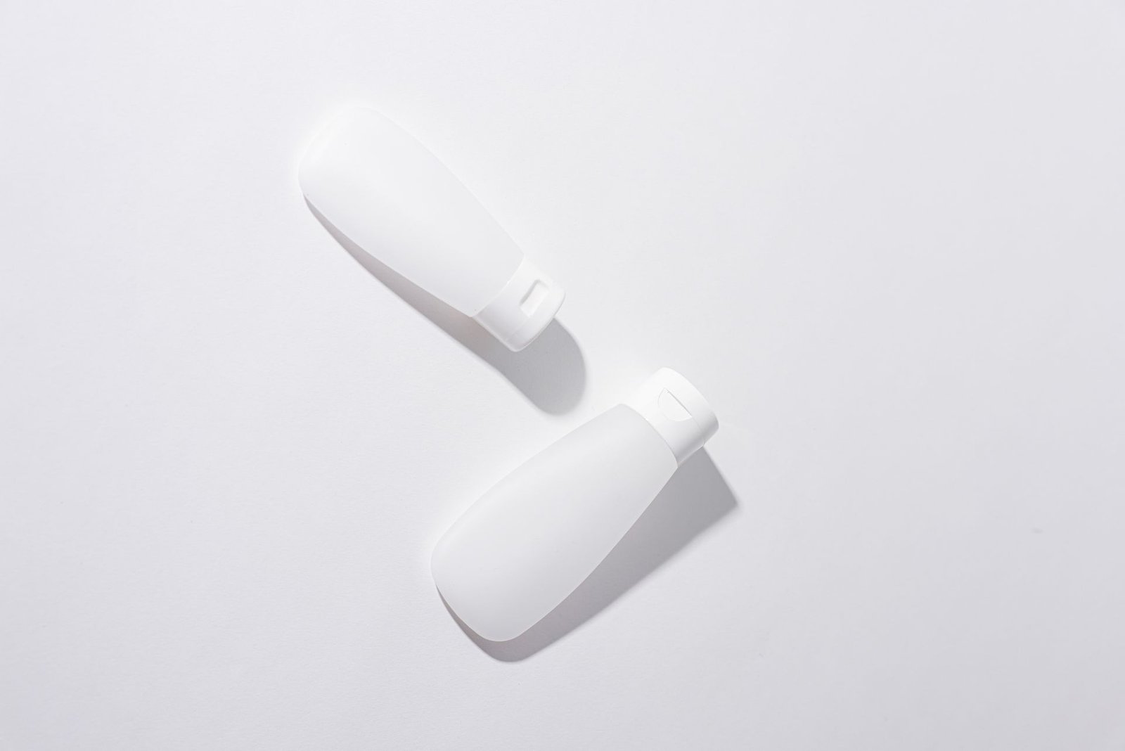 Two white cosmetic bottles in a minimalist flat lay