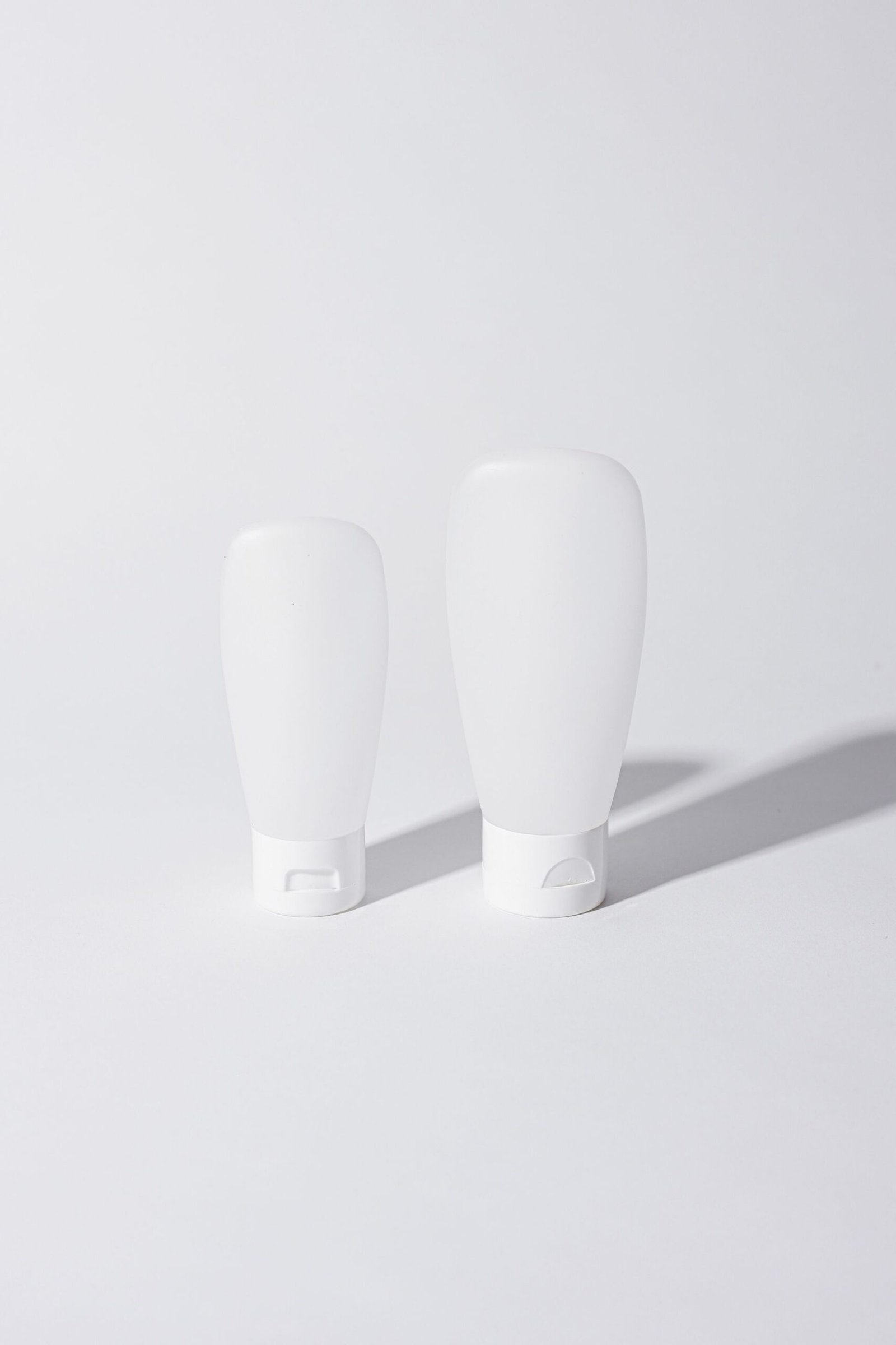 Two blank white cosmetic bottles on a white background