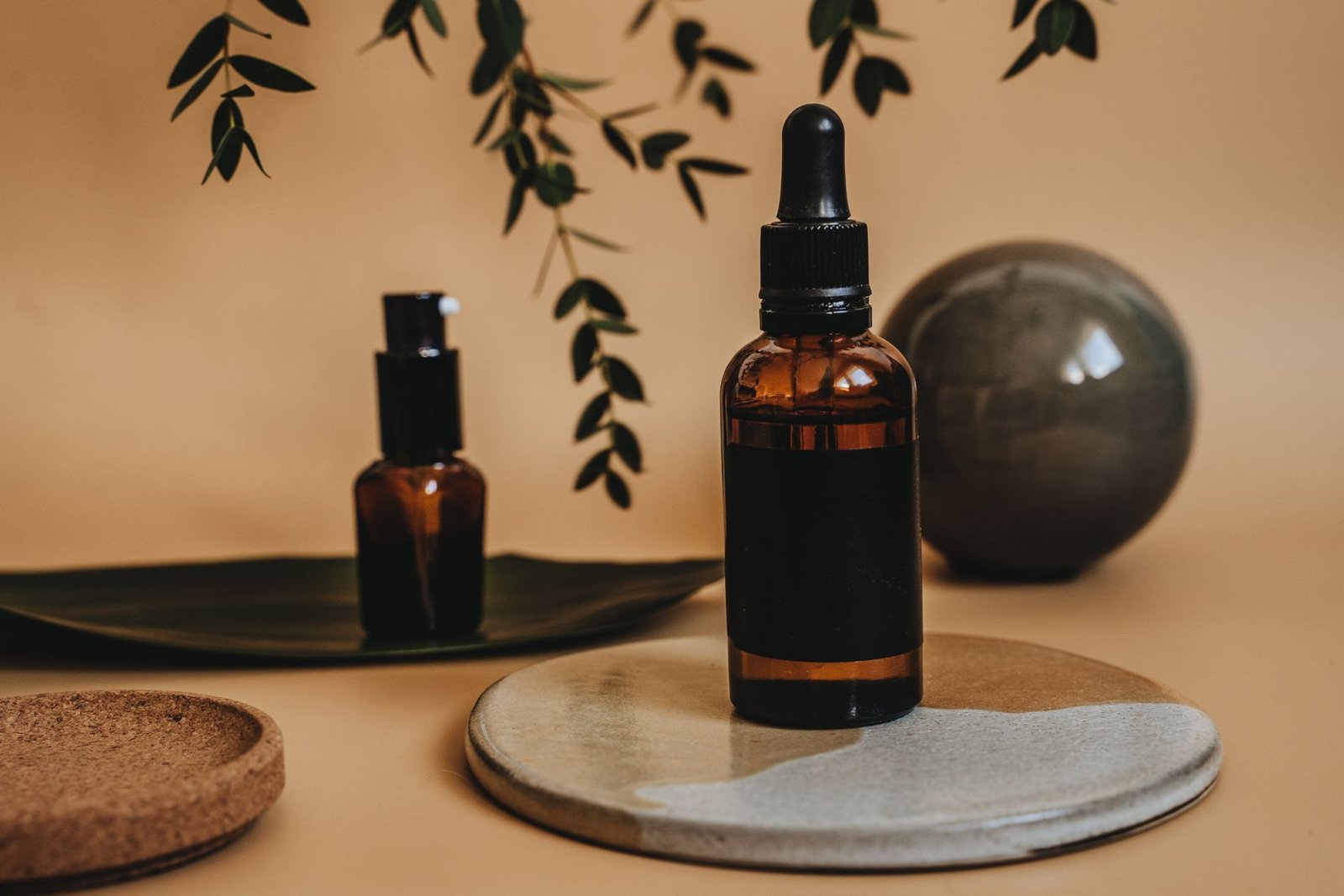 Amber dropper bottles with green leaves on a warm background