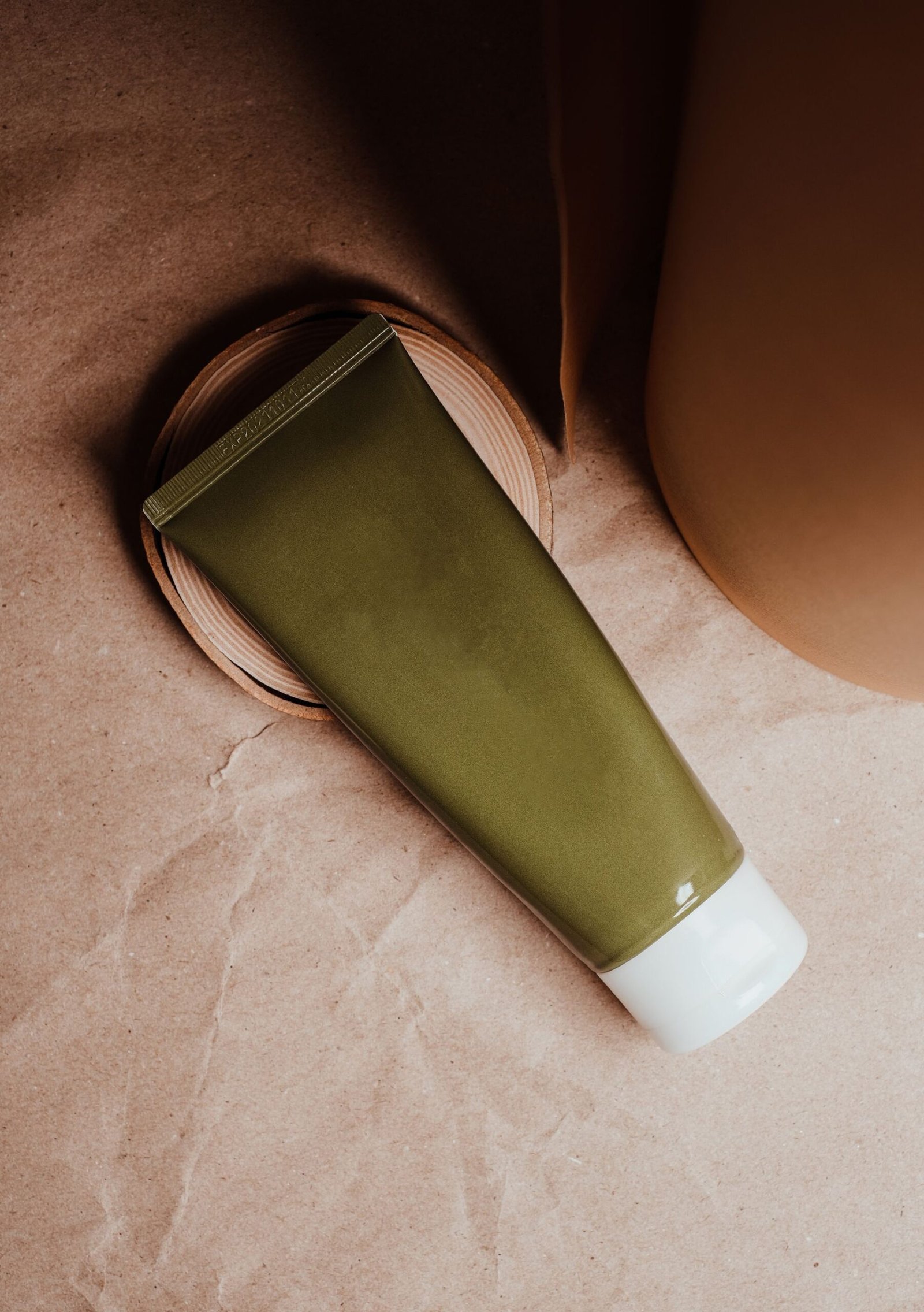 Olive green cosmetic tube on brown paper