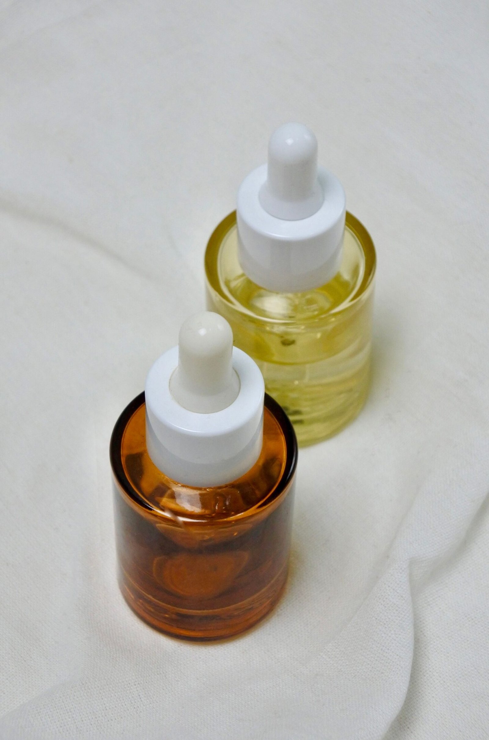 Two glass dropper bottles, one amber and one clear