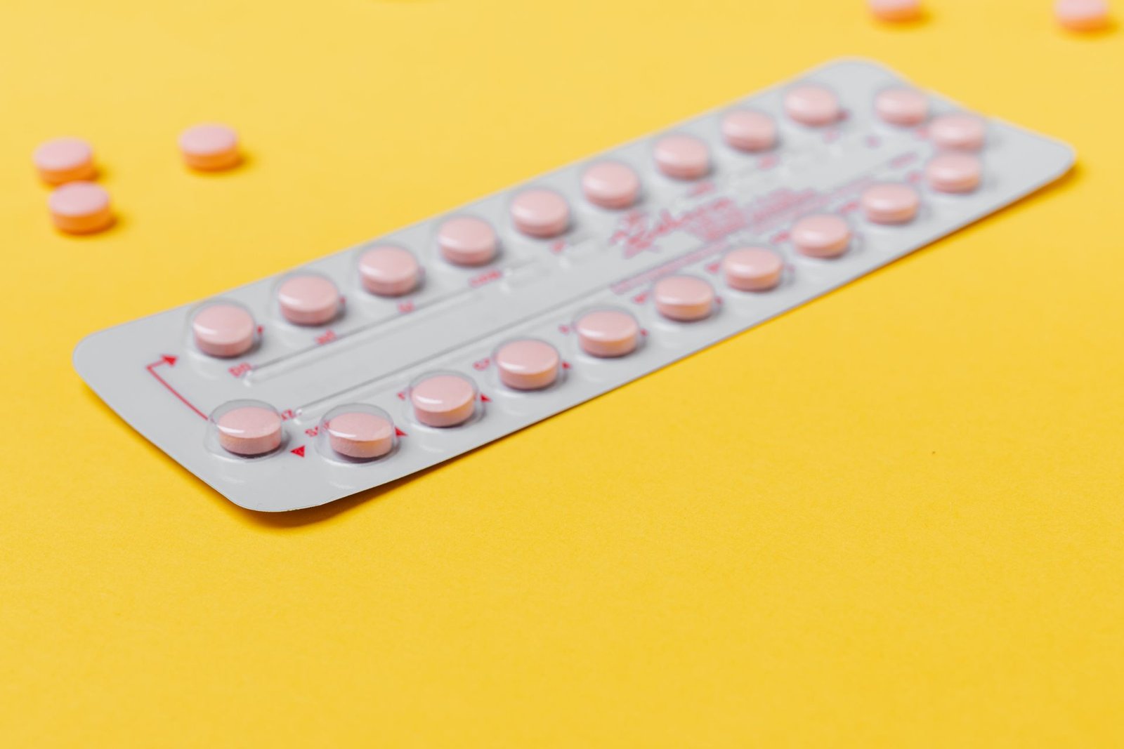 Blister pack of pink pills on a yellow background
