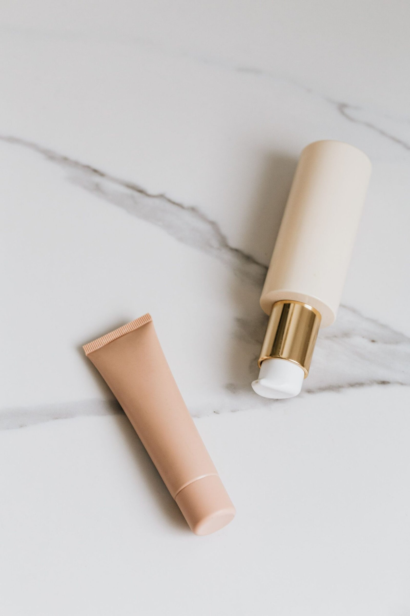 Two skincare tubes lying on white marble