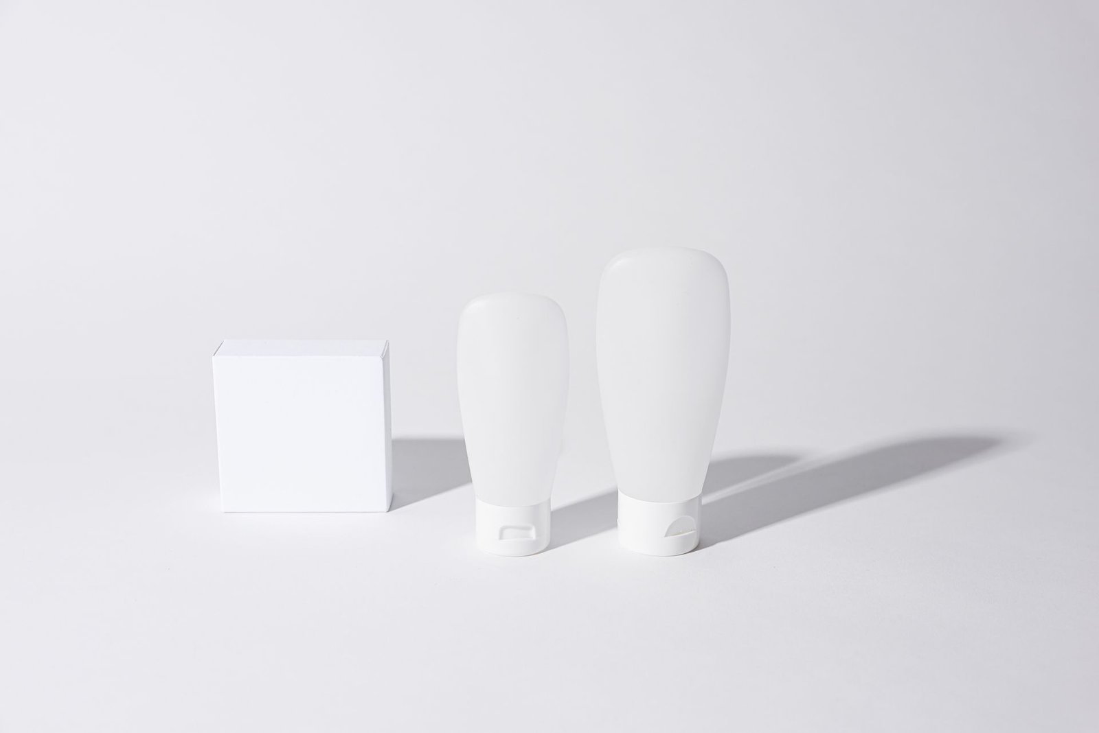Minimalist white cosmetic containers with soft shadows