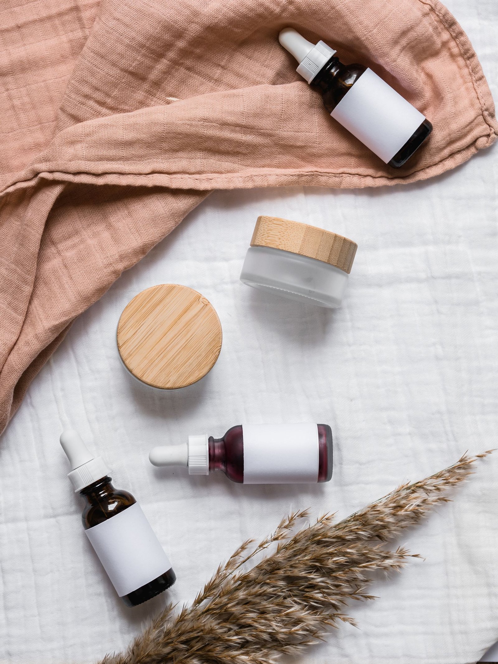 Flat lay of serum bottles and jars on soft fabric
