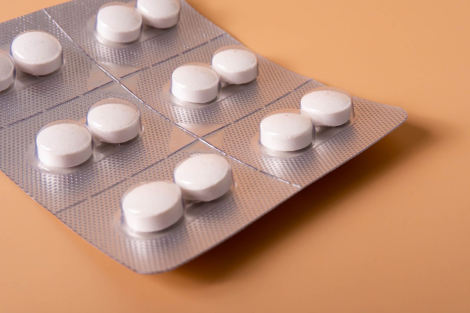White tablets in a blister pack on a peach background