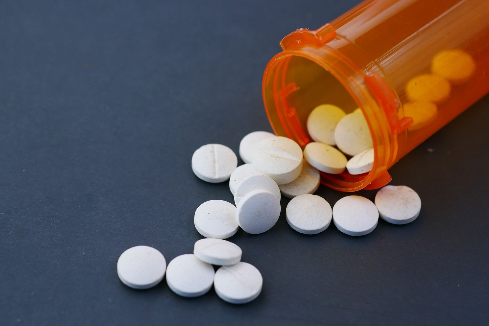 White tablets spilling from an orange prescription bottle