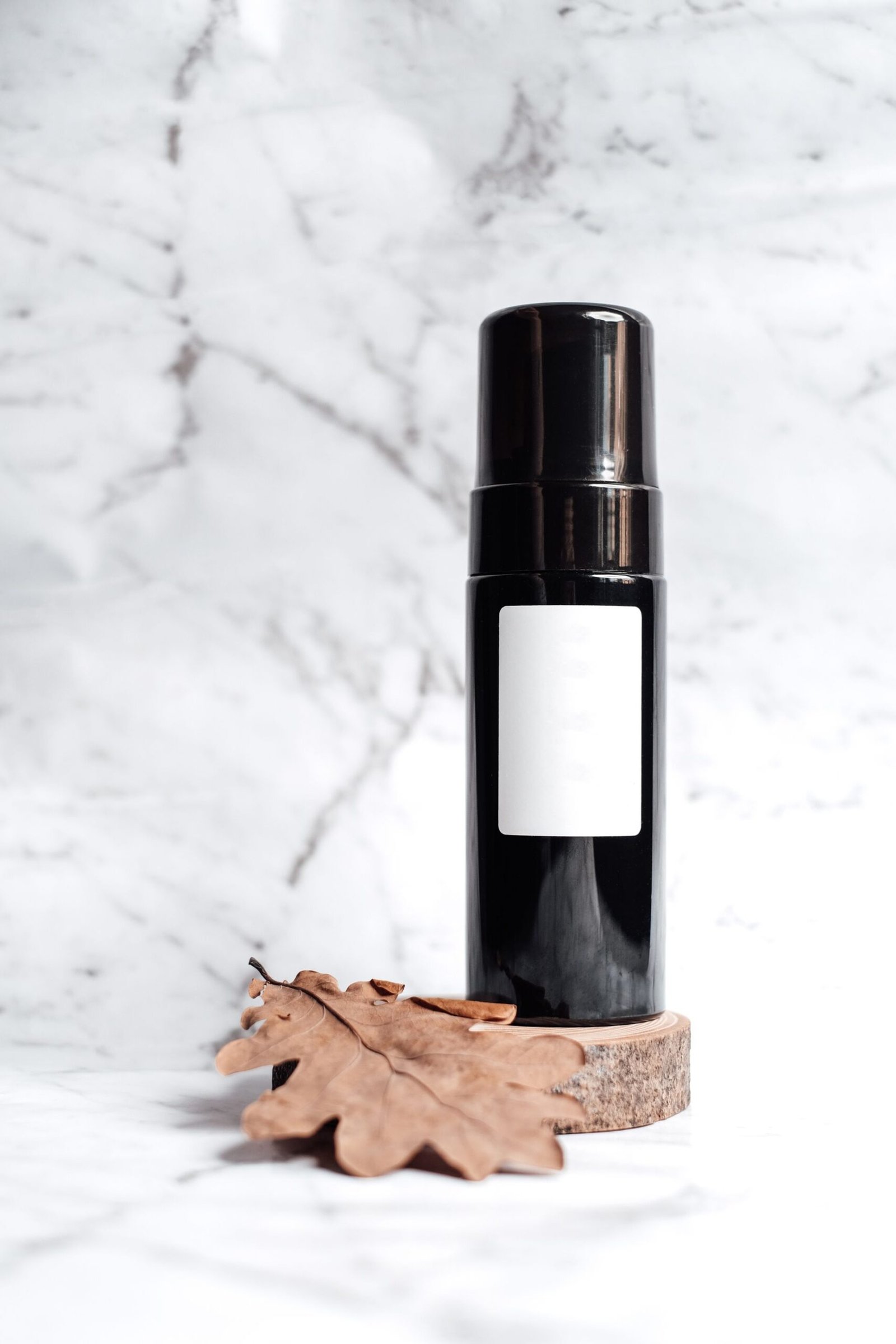 Dark cleanser bottle with a blank label on white marble